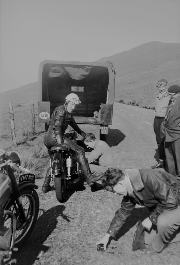Bill Doran (#68), his mechanic working on his motorcyle, Richard Seddon picking up tools in the foreground, and two other men
